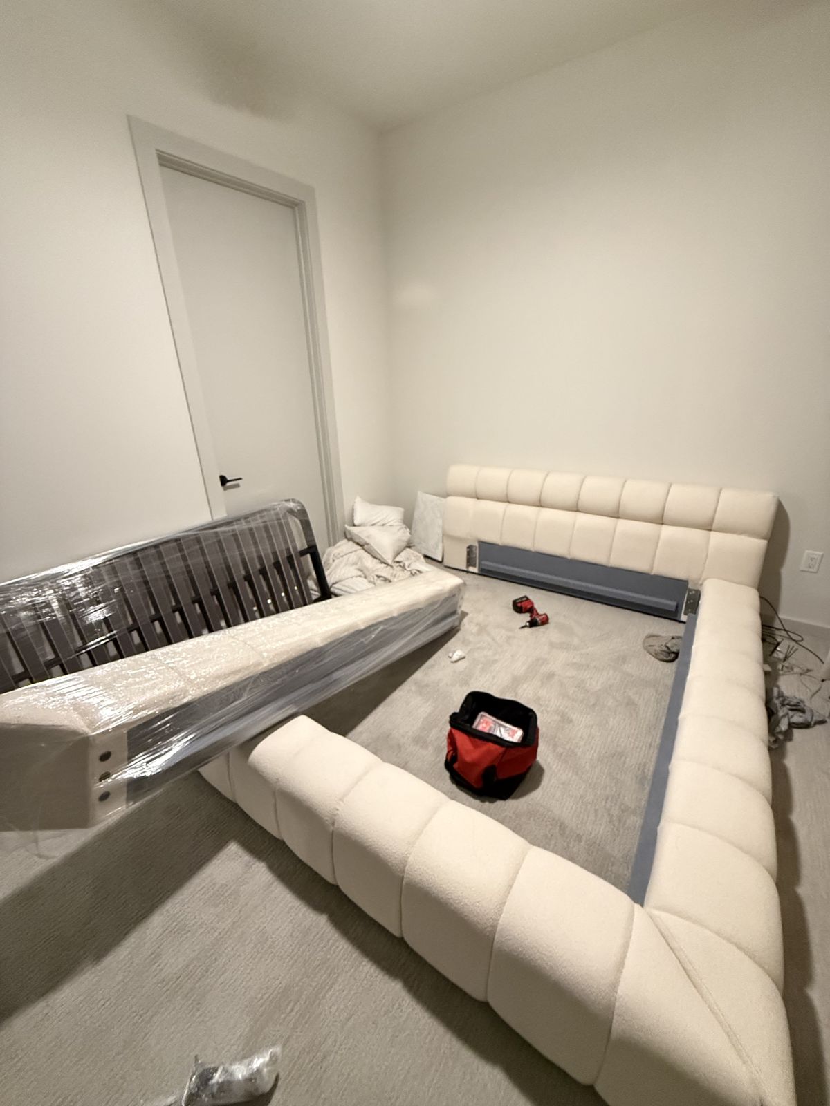 An upholstered bed has been disassembled, with its frame and wrapped components prepared for moving.