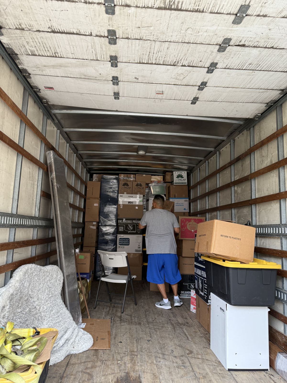 A TL Moving crew member organizes a large shipment of boxes and storage bins inside a box truck.