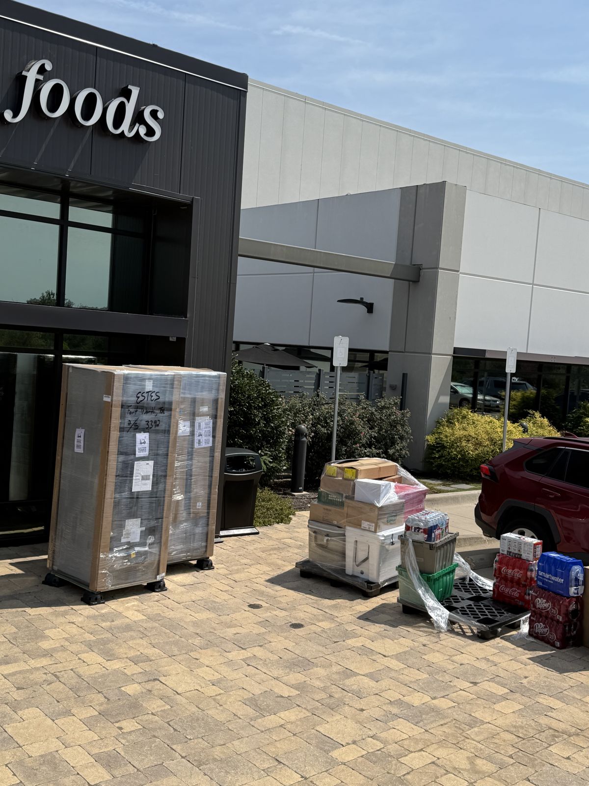 Wrapped commercial equipment and boxed merchandise are staged outside a storefront for transport.