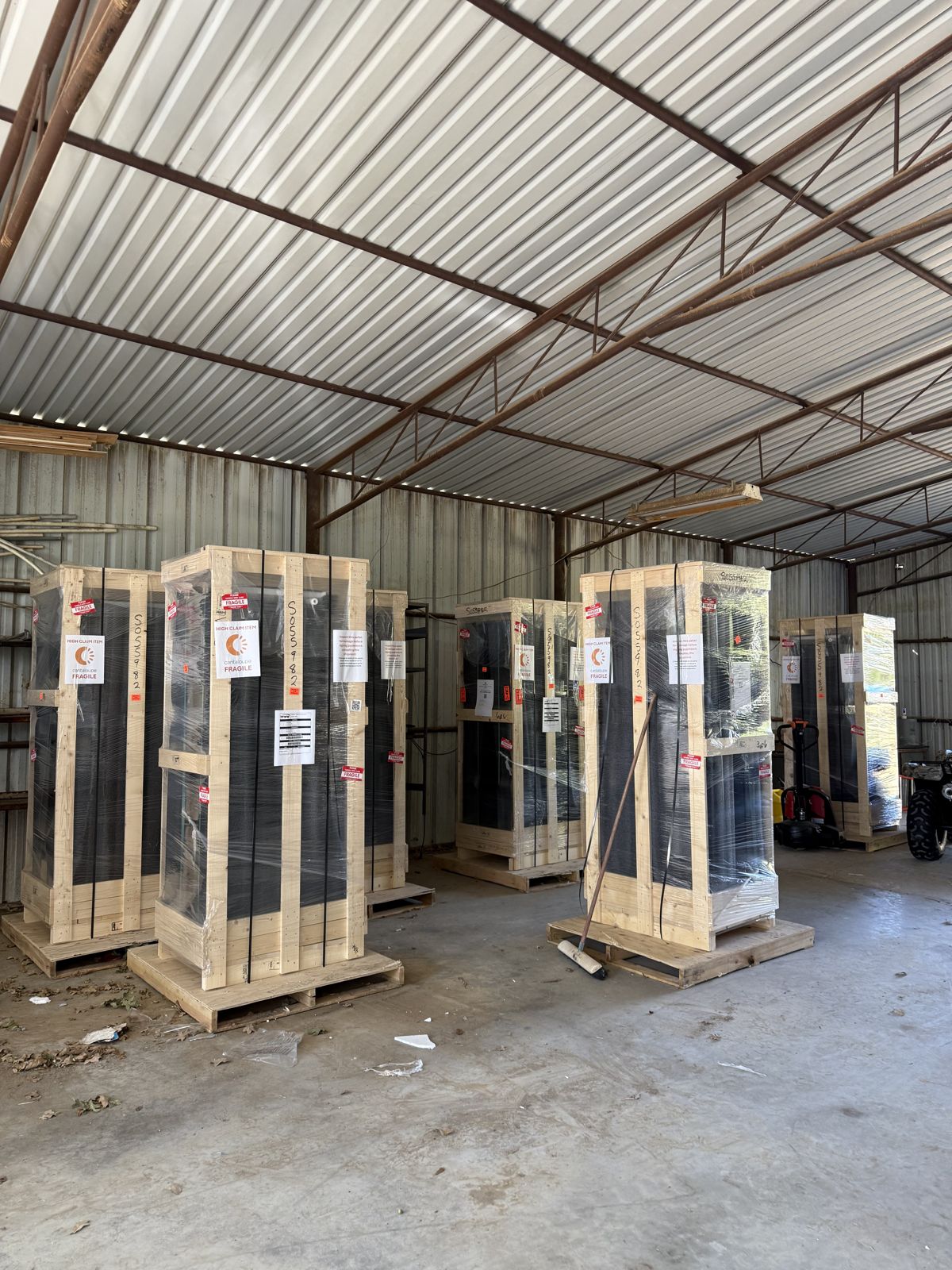 Several vending machines are wrapped and secured in wooden shipping crates inside a warehouse.