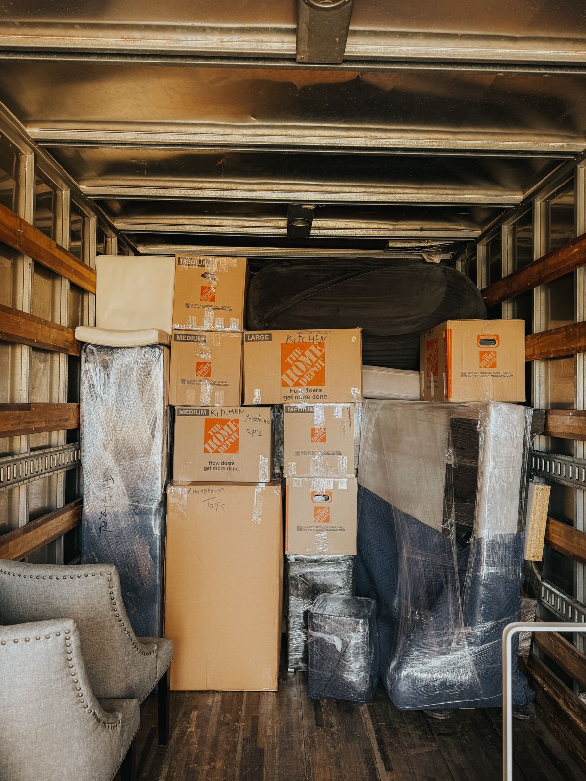 Boxes and carefully wrapped furniture are tightly arranged inside a moving truck.