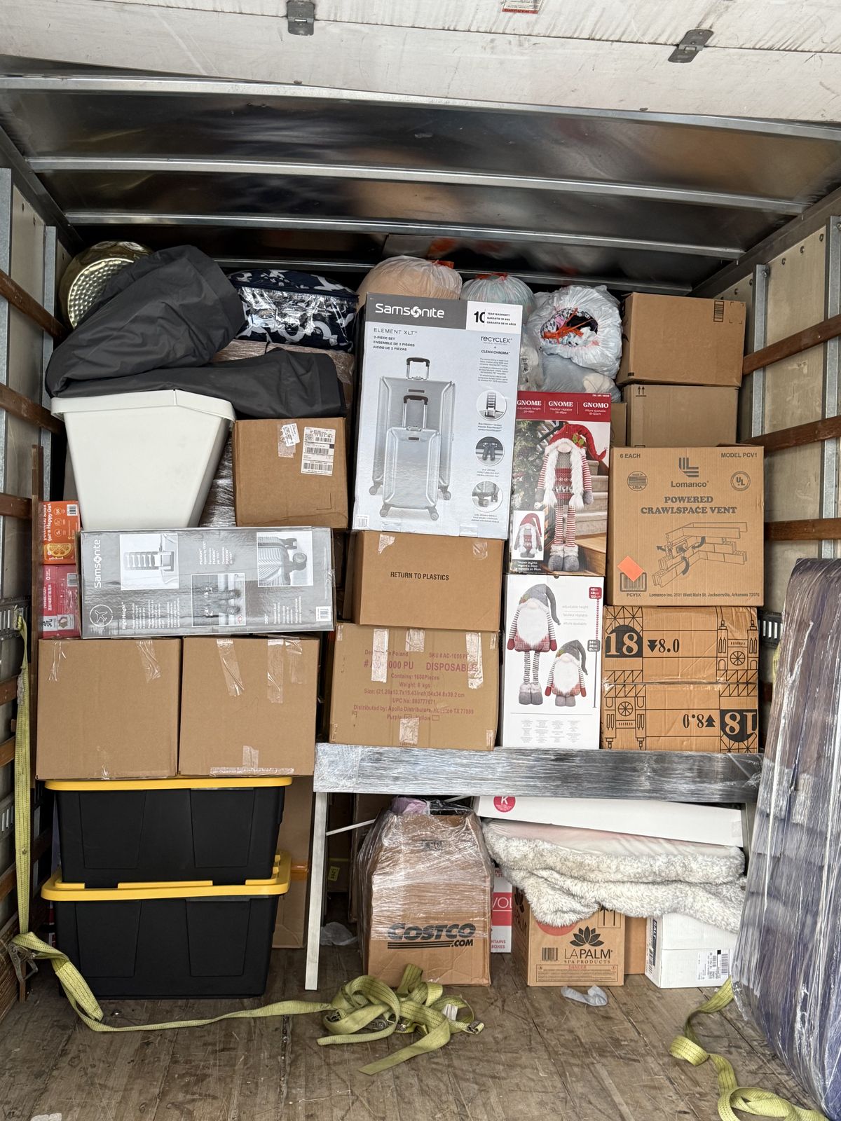 Boxes, storage bins, bedding, and wrapped household items are densely packed inside a TL Moving truck.