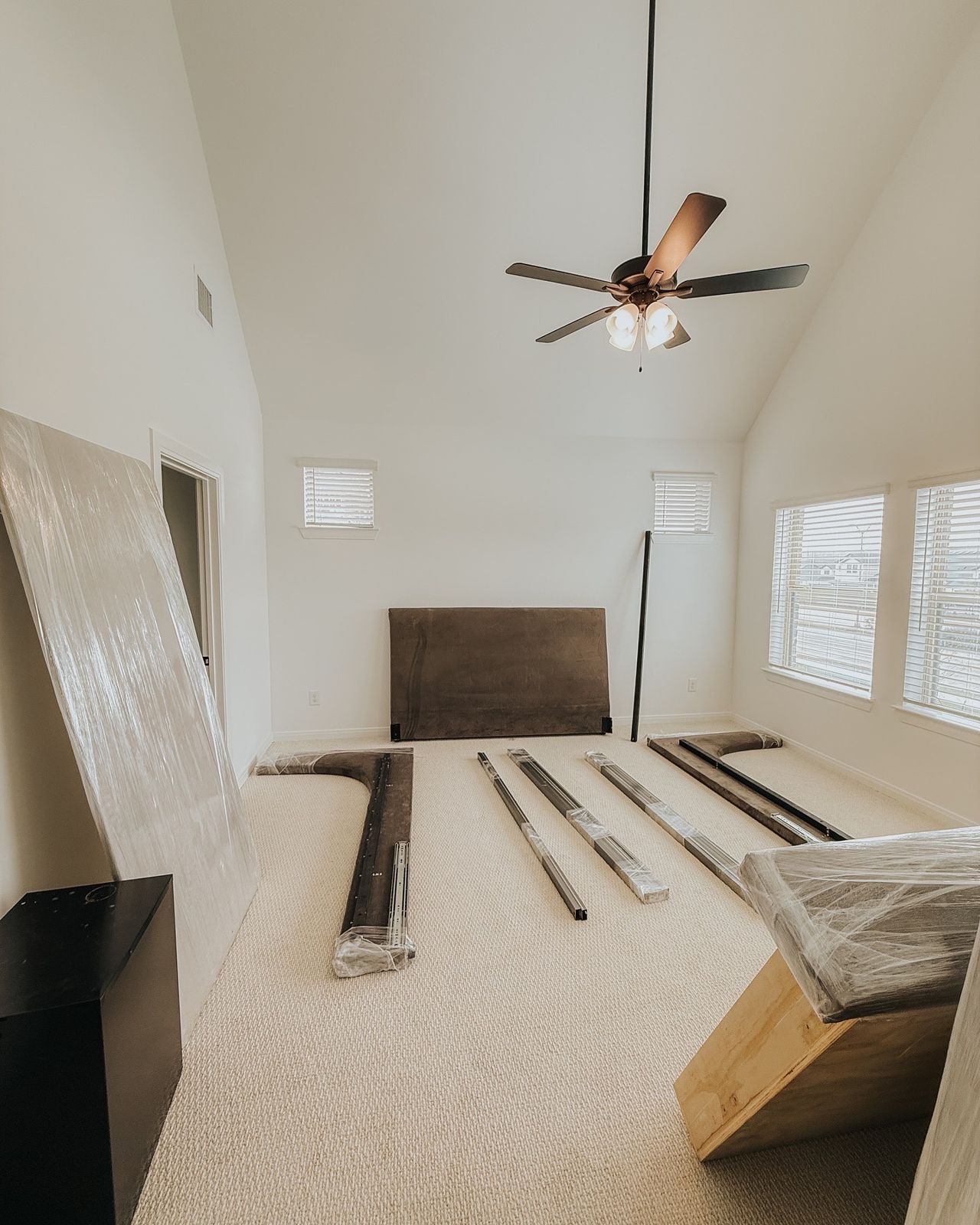 Wrapped furniture panels and disassembled frame pieces are organized across a bright residential room.