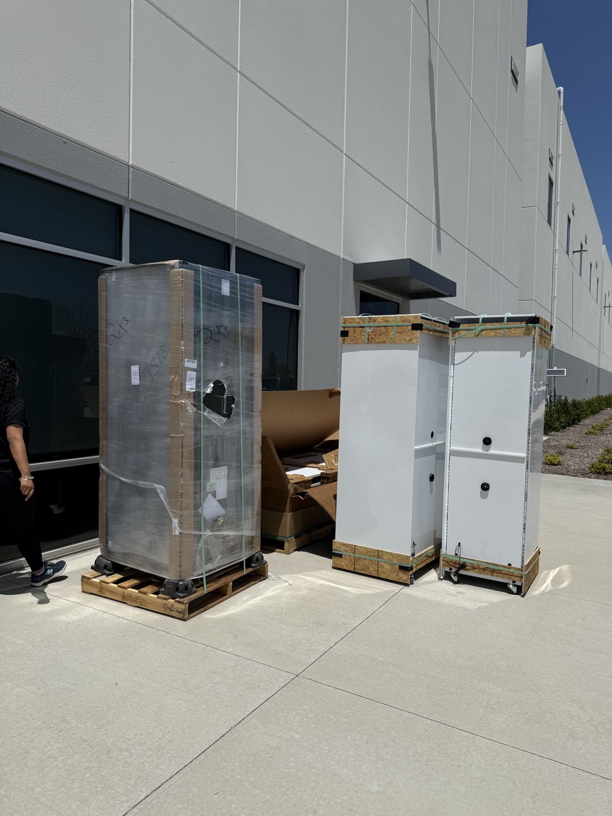 Three large commercial units are secured on pallets outside a warehouse for relocation.