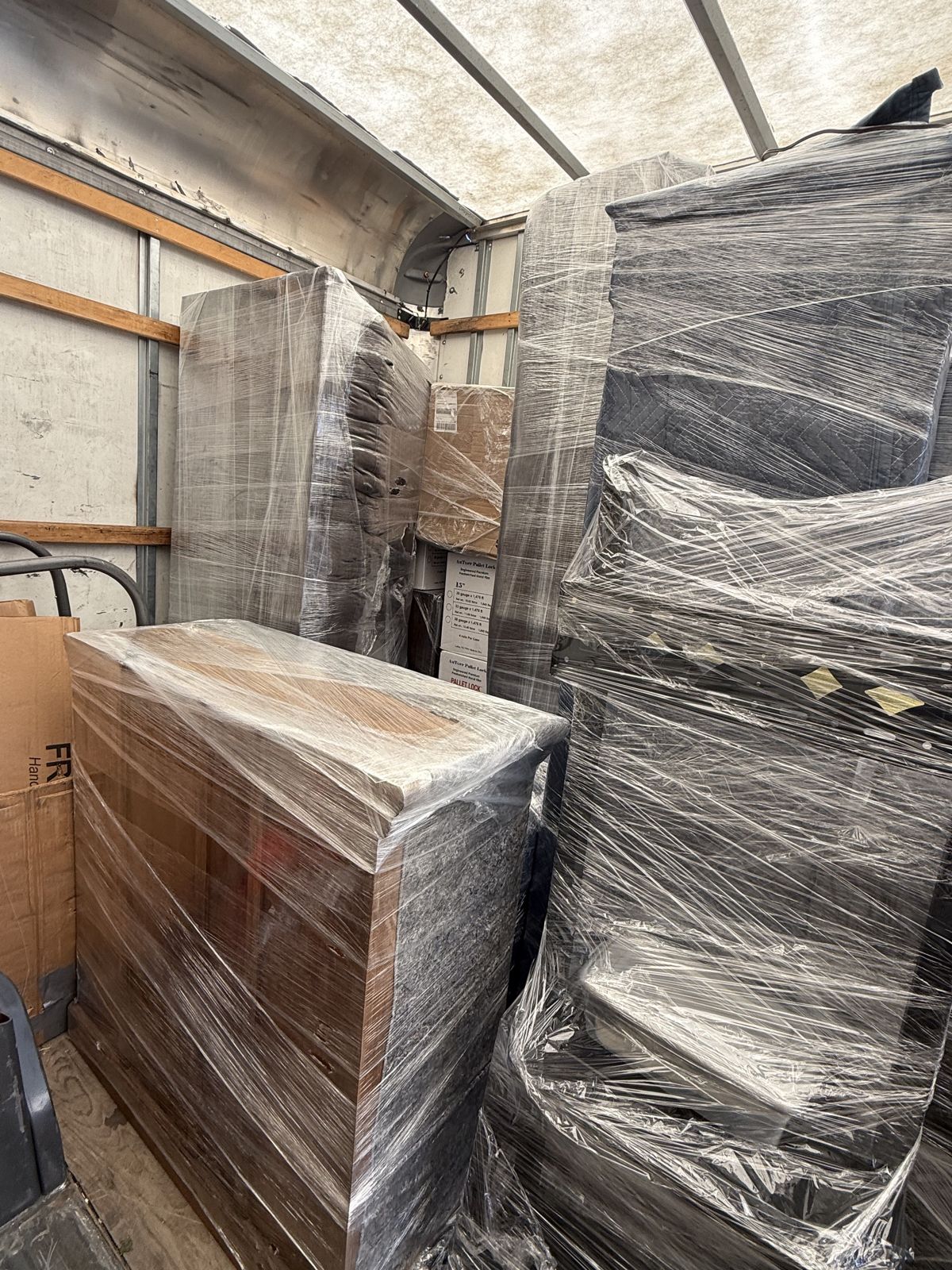 Commercial cabinets and fixtures are tightly shrink-wrapped inside a moving truck for protected transport.