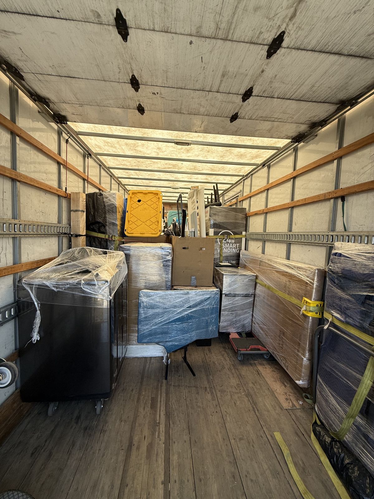 Wrapped furniture and household items are carefully arranged and secured throughout a moving truck.