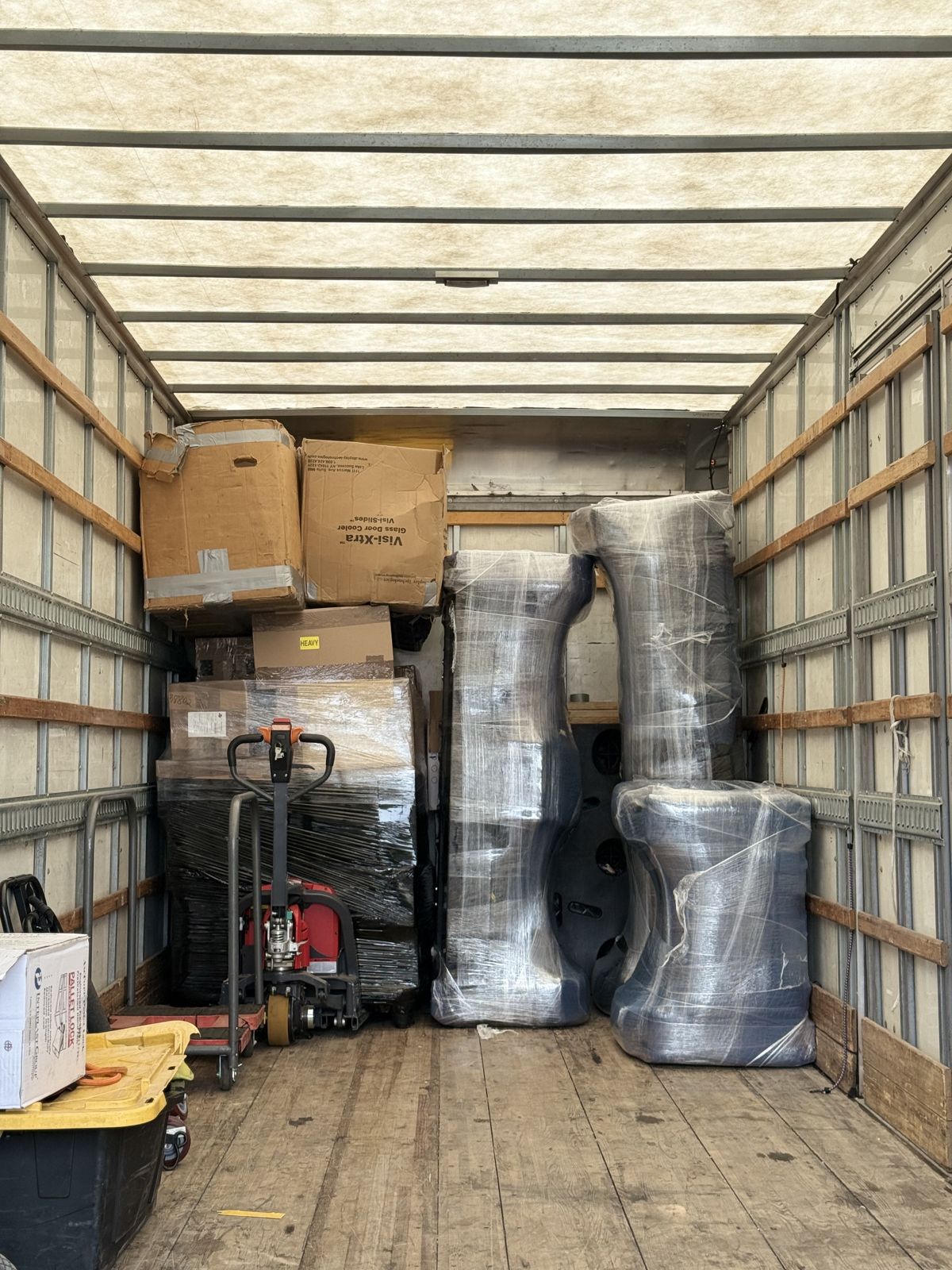 Wrapped furniture, packed cartons, and moving equipment are arranged inside a box truck.