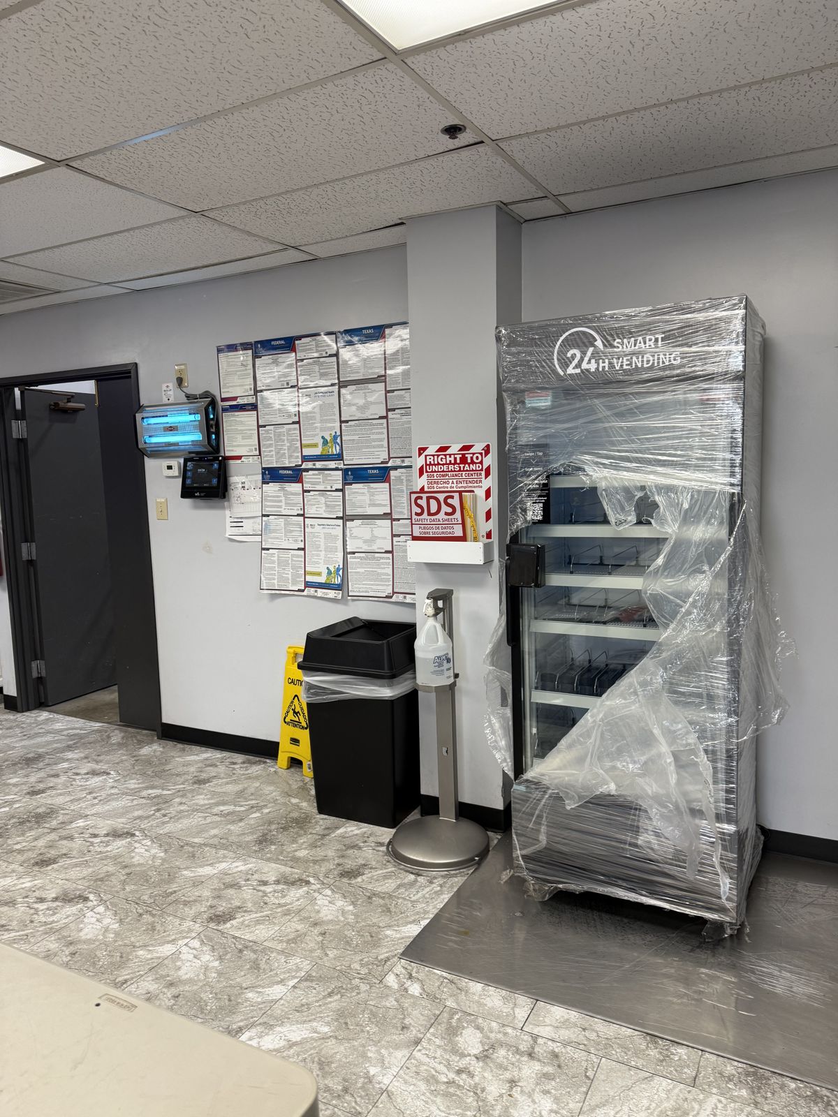 A smart vending machine stands partially wrapped for relocation inside a commercial facility.